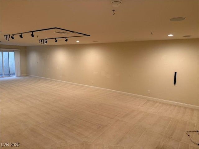 empty room featuring rail lighting and light colored carpet