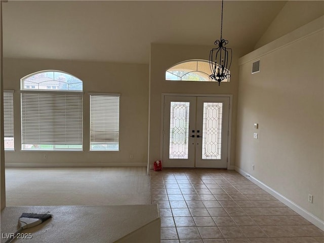 tiled entryway with french doors, high vaulted ceiling, and a healthy amount of sunlight