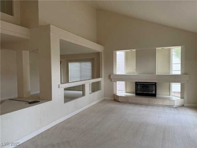 unfurnished living room featuring a tile fireplace, light colored carpet, and lofted ceiling