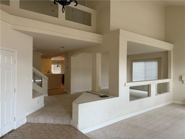 interior space featuring a high ceiling and light colored carpet