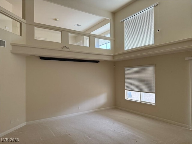 carpeted spare room with a towering ceiling