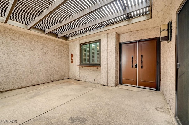 view of exterior entry featuring a pergola and a patio area