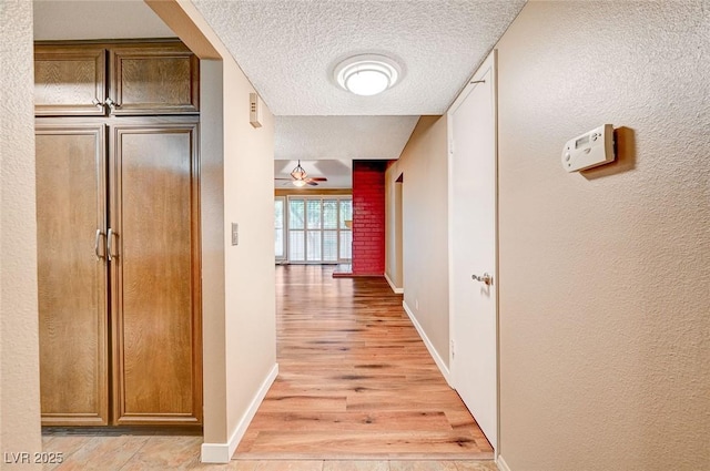 corridor featuring light hardwood / wood-style flooring and a textured ceiling