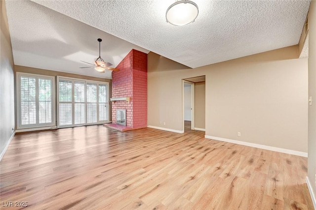 unfurnished living room featuring lofted ceiling, ceiling fan, light wood-type flooring, and a fireplace