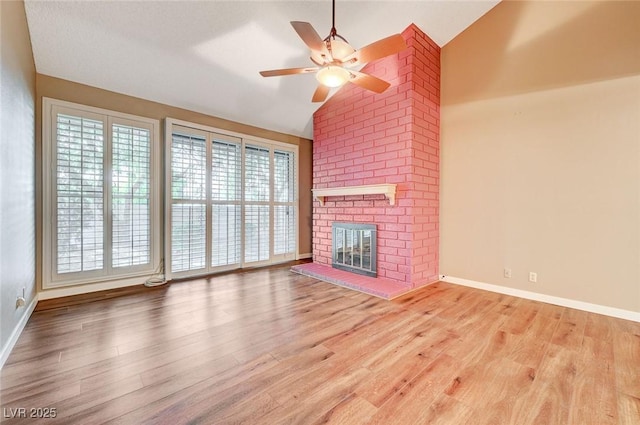 unfurnished living room with ceiling fan, light hardwood / wood-style floors, lofted ceiling, and a brick fireplace