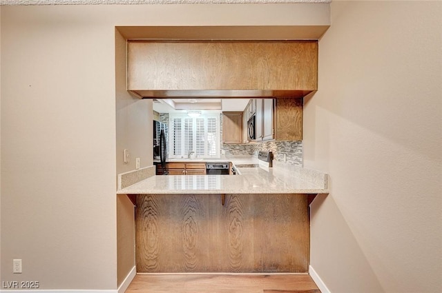 kitchen with refrigerator, sink, light wood-type flooring, tasteful backsplash, and stainless steel range oven