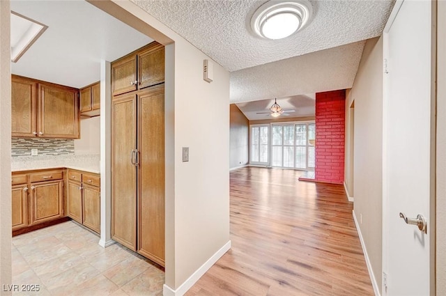 hallway with light wood-type flooring and a textured ceiling