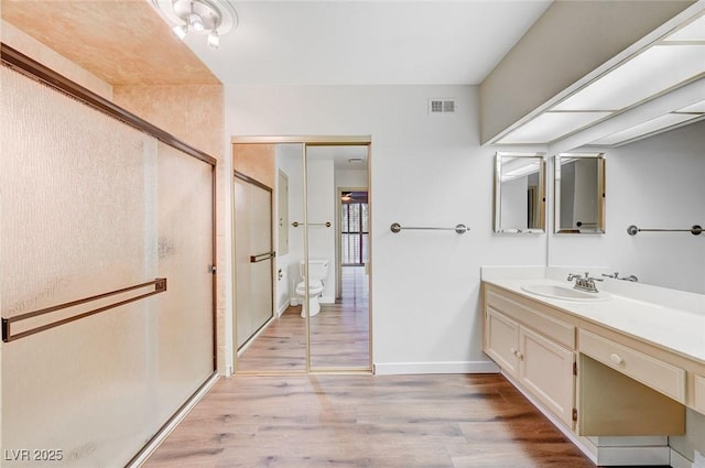 bathroom with hardwood / wood-style flooring, vanity, an enclosed shower, and toilet