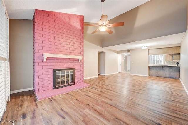 unfurnished living room featuring light hardwood / wood-style flooring, a brick fireplace, ceiling fan, and lofted ceiling