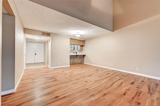 unfurnished living room featuring a textured ceiling and light hardwood / wood-style flooring