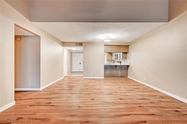 unfurnished living room with a textured ceiling and light wood-type flooring