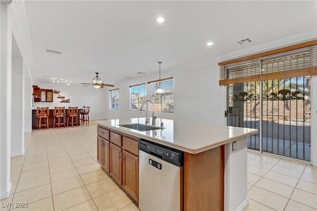 kitchen featuring dishwasher, an island with sink, light tile patterned floors, sink, and decorative light fixtures