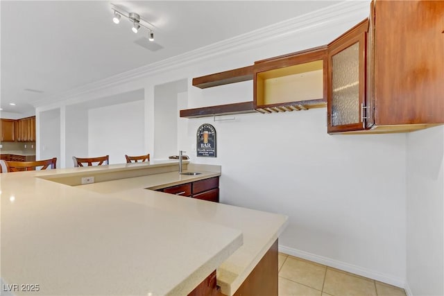 kitchen featuring a breakfast bar area, crown molding, kitchen peninsula, light tile patterned floors, and sink