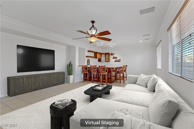 living room with crown molding, bar area, ceiling fan, and light tile patterned floors