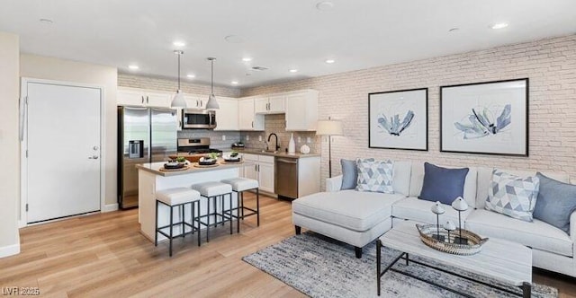 living room with light wood-type flooring, sink, and brick wall