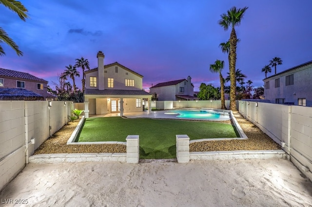 pool at dusk featuring a yard and a patio