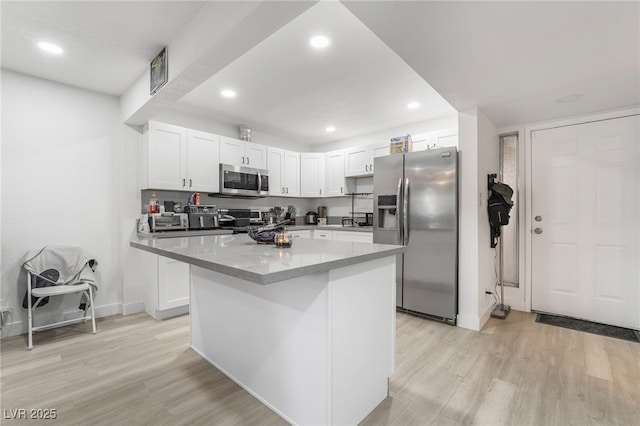 kitchen with white cabinets, appliances with stainless steel finishes, light wood-type flooring, and a kitchen island