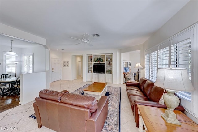 living room with light tile patterned flooring, ceiling fan, and built in shelves