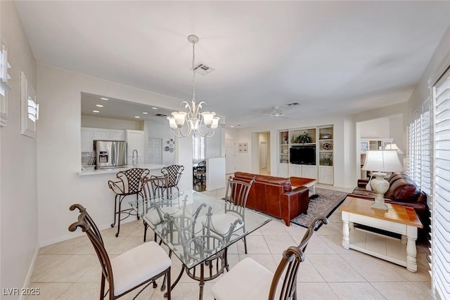 tiled dining room with ceiling fan with notable chandelier and built in shelves