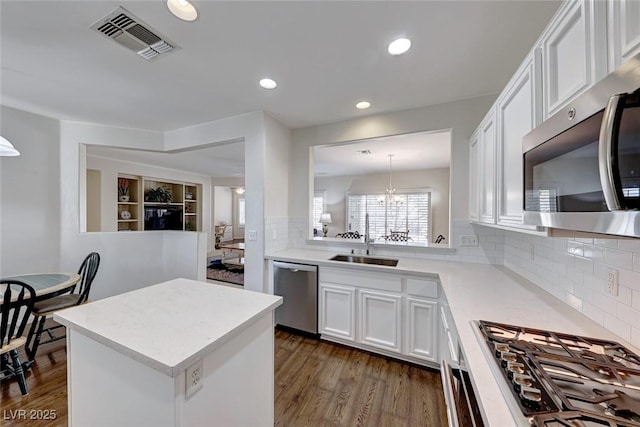 kitchen with white cabinetry, stainless steel appliances, hanging light fixtures, and backsplash