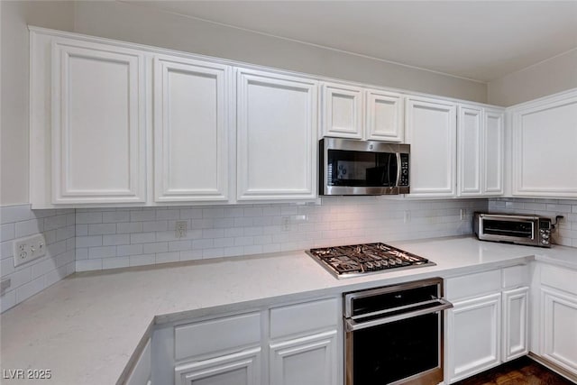 kitchen featuring backsplash, appliances with stainless steel finishes, and white cabinets