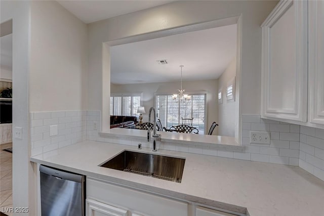 kitchen with dishwasher, sink, white cabinets, and an inviting chandelier