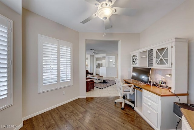 office area with ceiling fan, built in desk, and light wood-type flooring