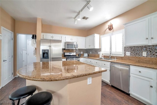 kitchen with a center island, light stone countertops, white cabinetry, and appliances with stainless steel finishes