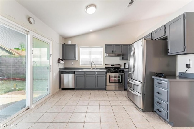 kitchen with appliances with stainless steel finishes, gray cabinetry, vaulted ceiling, sink, and light tile patterned floors