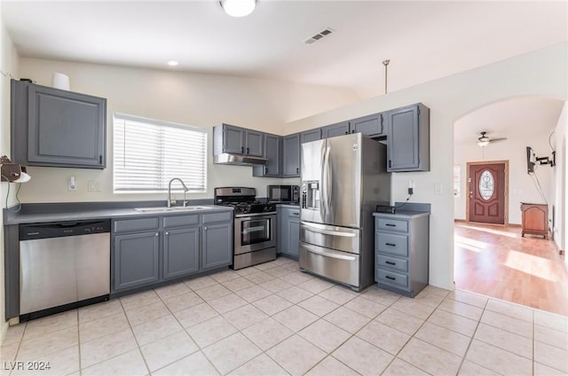 kitchen featuring gray cabinetry, sink, lofted ceiling, light tile patterned flooring, and appliances with stainless steel finishes