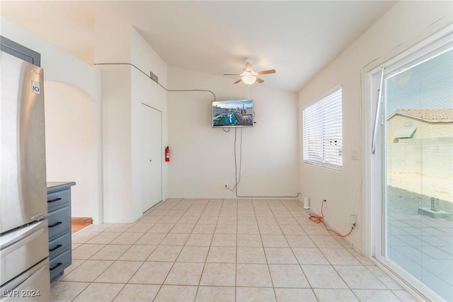 empty room with light tile patterned floors, vaulted ceiling, and ceiling fan