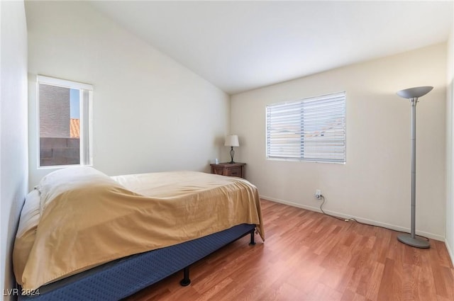 bedroom with hardwood / wood-style floors and lofted ceiling