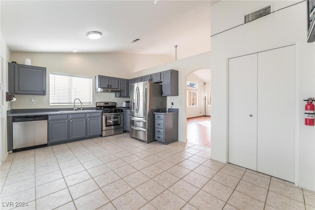 kitchen featuring stainless steel appliances, vaulted ceiling, sink, light tile patterned floors, and gray cabinets