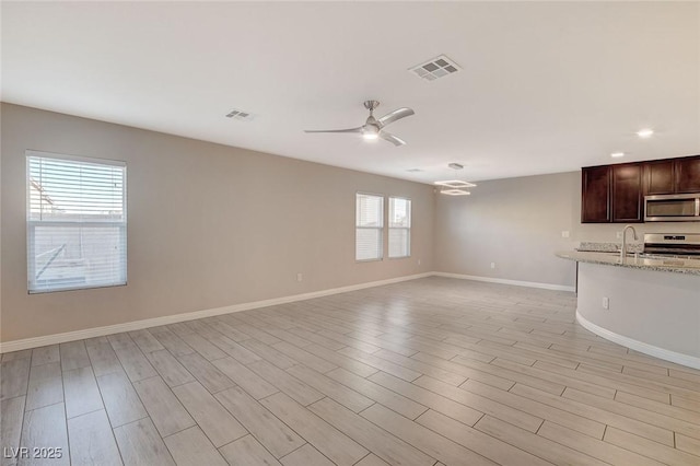 unfurnished living room with a wealth of natural light, ceiling fan, and light hardwood / wood-style floors