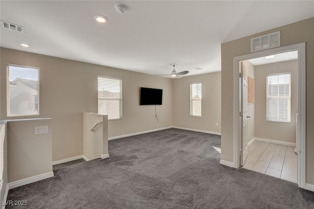 carpeted empty room with ceiling fan and a wealth of natural light