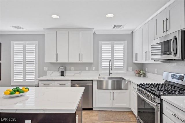 kitchen with white cabinets, stainless steel appliances, crown molding, and sink