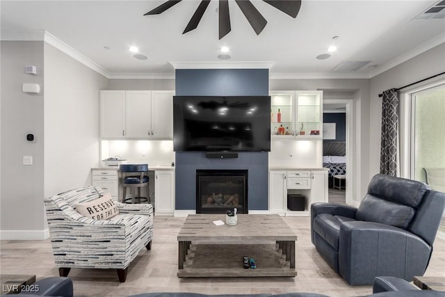 living room with ceiling fan, light hardwood / wood-style floors, crown molding, and a fireplace