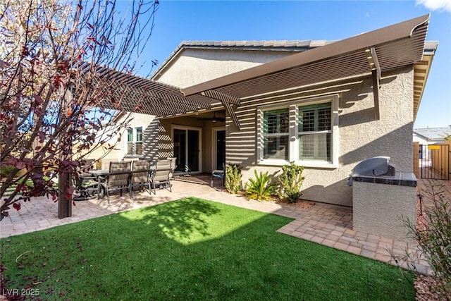 rear view of property featuring a pergola, an outdoor kitchen, a patio area, and a lawn