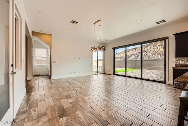 empty room featuring a mountain view, a chandelier, and light hardwood / wood-style flooring