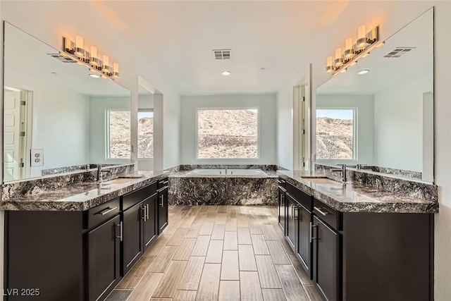 bathroom with vanity and tiled bath