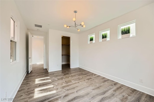 unfurnished bedroom featuring a notable chandelier, wood-type flooring, and a closet