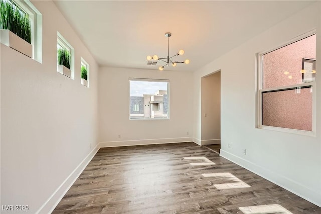 spare room featuring an inviting chandelier and hardwood / wood-style flooring