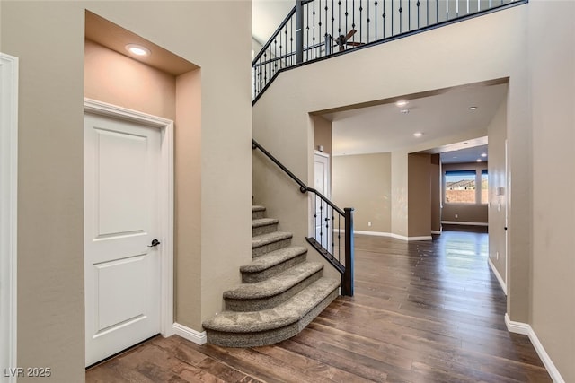 staircase featuring wood-type flooring and a towering ceiling