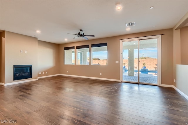 unfurnished living room with dark hardwood / wood-style flooring and ceiling fan