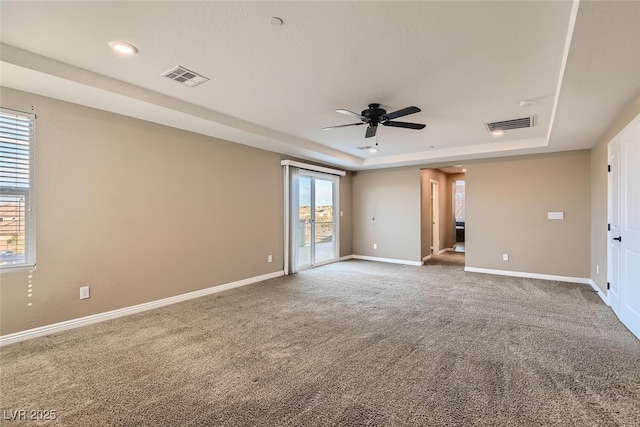 unfurnished room with ceiling fan, carpet floors, and a tray ceiling