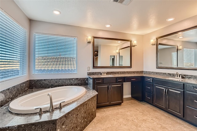 bathroom with tiled tub and vanity