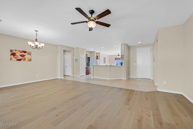 unfurnished living room featuring ceiling fan with notable chandelier and light hardwood / wood-style floors