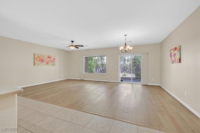 empty room with light hardwood / wood-style floors and ceiling fan with notable chandelier