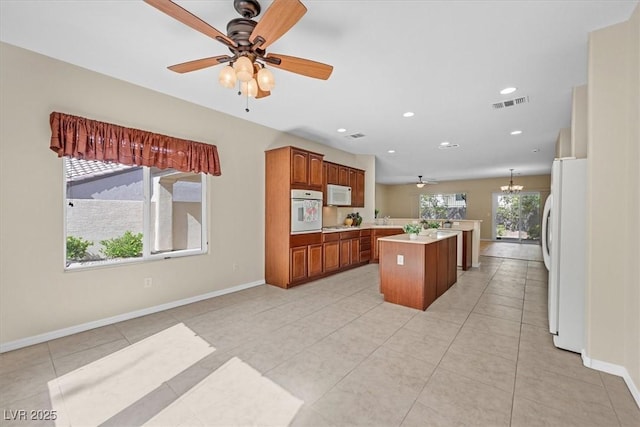 kitchen featuring a center island, white appliances, ceiling fan with notable chandelier, hanging light fixtures, and light tile patterned floors