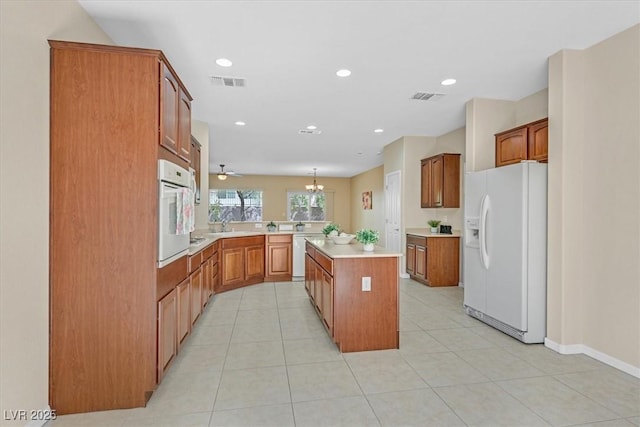 kitchen with a kitchen island, kitchen peninsula, decorative light fixtures, white appliances, and light tile patterned floors